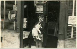 Fotografía [Miguel Ángel Lens con un gato frente a un almacén]